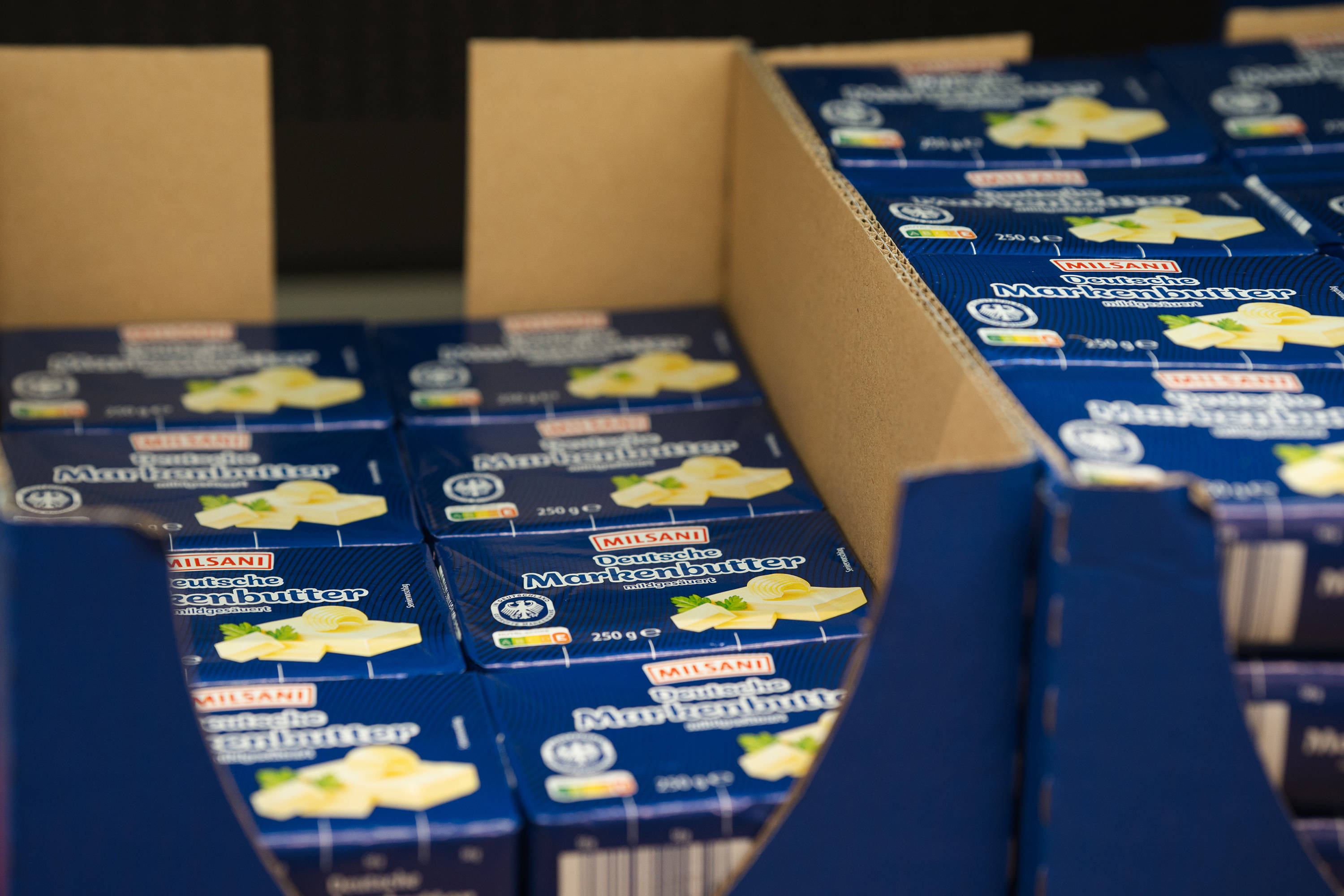 Nahaufnahme mehrerer Packungen ALDI Milsani Deutsche Markenbutter in einem Karton im ALDI-Regal.