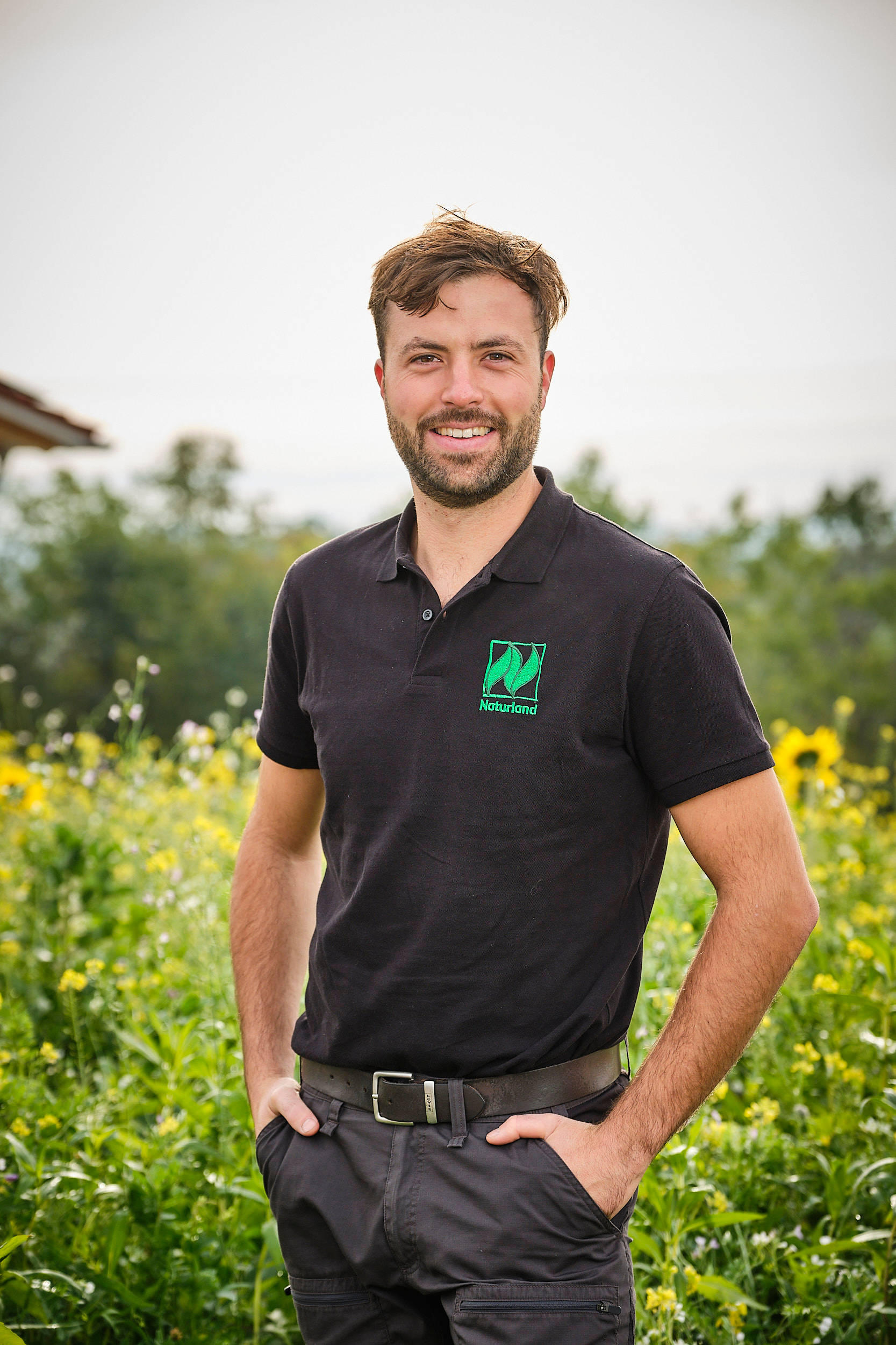 Naturland-Landwirt Stefan Meier steht vor einer blühenden Anbaufläche.