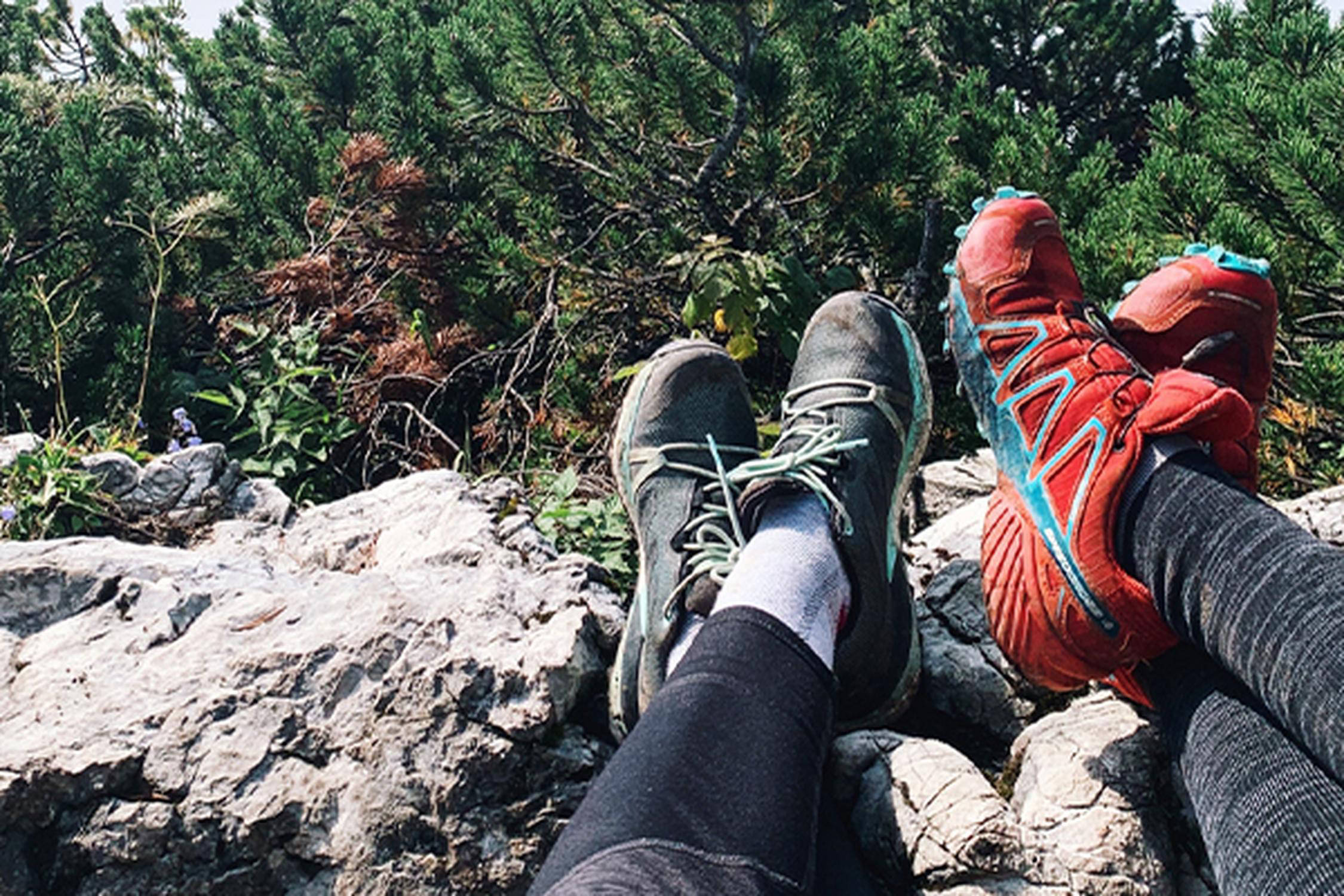 vier Füße mit Wanderschuhen liegen auf einem Stein
